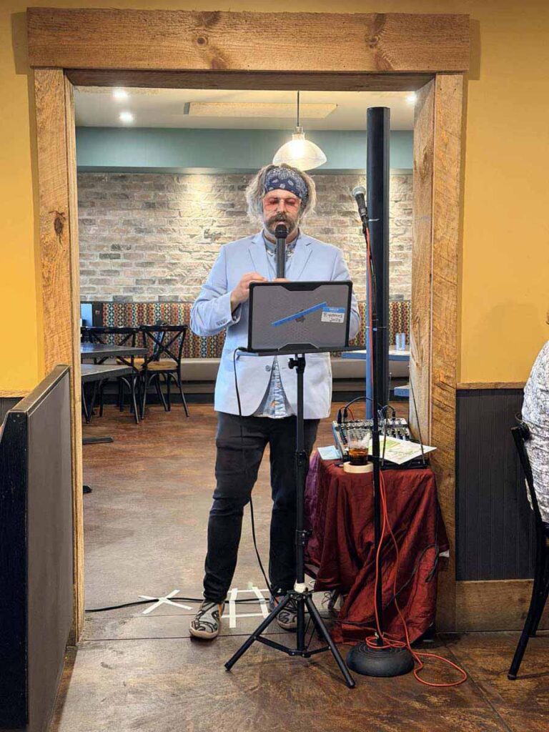 male standing reading from a laptop