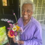 female holding a container filled with flowers