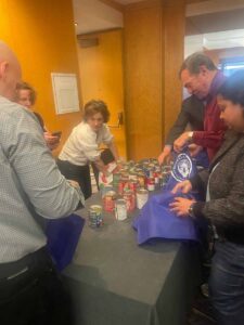 people standing around a table that has cans of soup on it